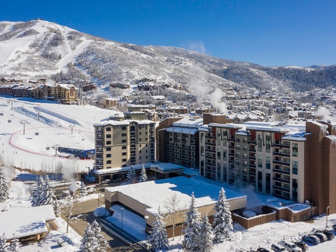 Aerial view of the property nestled at the base of snow-covered ski slopes in a scenic mountain resort town, offering convenient slope-side access.