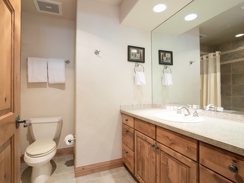 Refresh in your private bathroom with warm wood cabinetry, ample vanity space, and fresh towels waiting for you after a relaxing shower.