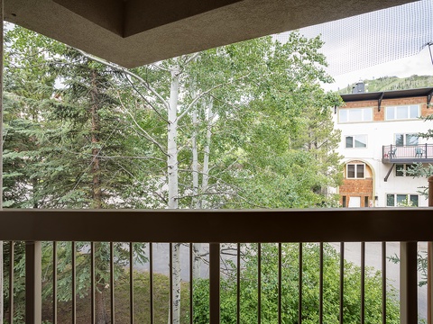 A covered porch frames views of aspen trees and nearby properties, offering a pleasant outdoor retreat for your mountain stay.