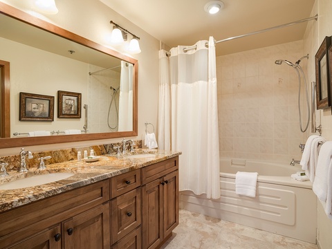 Unwind in a spacious bathroom with dual sinks, a soaking tub, and a refreshing walk-in shower. Plush towels and warm wood finishes create a welcoming retreat for your daily rituals.