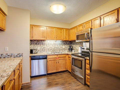 Your fully equipped kitchen awaits with stainless steel appliances, stylish mosaic tile backsplash, and warm wood cabinetry—everything you need to prepare meals in comfort.