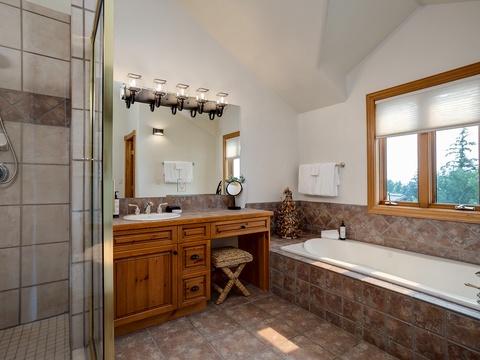Unwind in your private spa-like bathroom with a soaking tub, tiled shower, dual vanity, and natural light framing peaceful views.