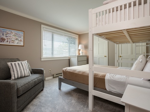 Your cozy bedroom features a comfy sofa for lounging, a bunk bed for flexible sleeping arrangements, and soft natural light filtering through the window—perfect for restful nights and relaxed mornings.