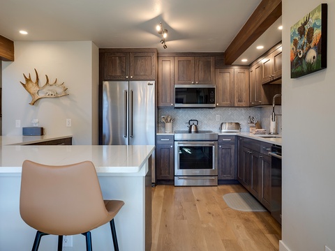 Your beautifully appointed kitchen features custom cabinetry, stainless appliances, and a sleek breakfast bar—perfect for whipping up morning coffee or evening meals.