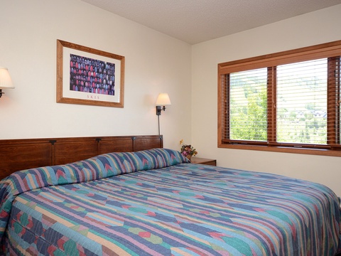 Settle into your cozy bedroom with warm wood accents, cheerful artwork, and natural light streaming through the windows, inviting you to relax and recharge.