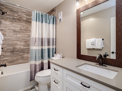 Refresh in your private bathroom with a sleek vanity, wood-grain tile shower-tub, and soft towels ready for your arrival.