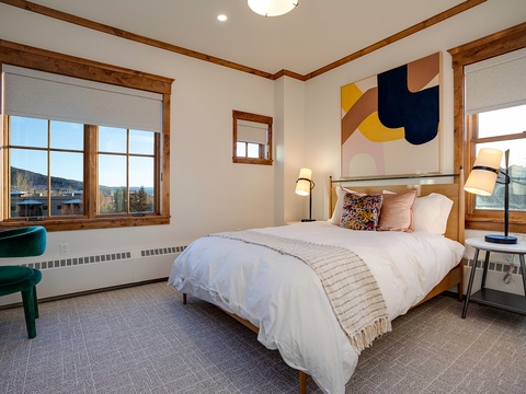 Drift off in your peaceful retreat with plush bedding, warm wood accents, and stunning mountain and lake views framing both sides of your cozy bedroom.