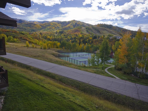 Scenic mountain property featuring tennis courts nestled among vibrant fall foliage, with expansive hillside views and outdoor recreation facilities throughout the grounds.