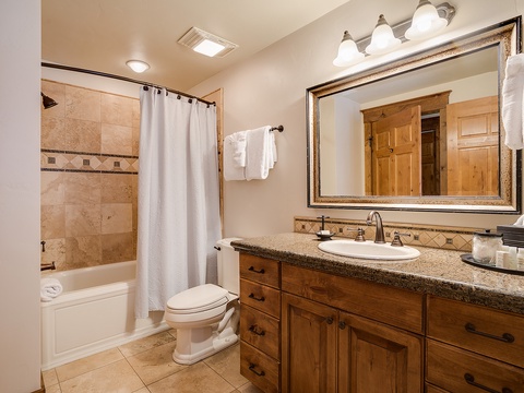 Unwind in your elegant bathroom with granite counters, custom cabinetry, plush towels, and a soothing tiled shower—everything you need for a refreshing escape.