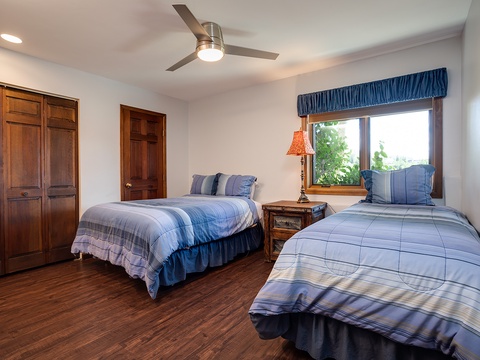 Rest easy in your comfortable twin bedroom with soft blue linens, warm wood tones, and a ceiling fan to keep you cool. Natural light streams in, offering a peaceful retreat.
