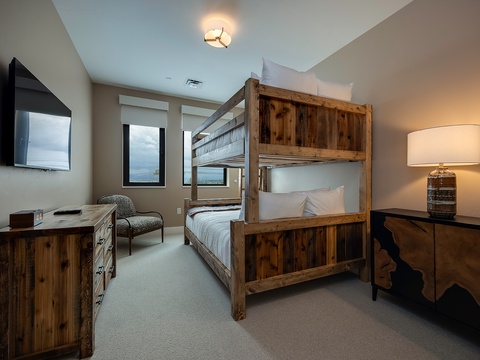 Rustic wood bunks and warm lighting create a cozy retreat where you can unwind after a day of adventure, with views to enjoy from your window.