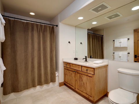 Step into your private bathroom with warm wood cabinetry, fresh towels, and a spacious shower—everything you need to refresh after a day of adventure.