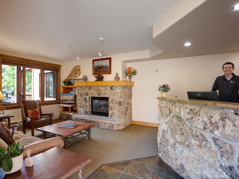 Welcome desk with friendly staff ready to greet you in a cozy lobby with stone fireplace and comfortable seating for your arrival.