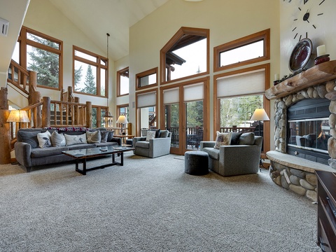 Sink into plush seating by your stone fireplace while soaking in natural light and forest views through soaring windows—your perfect mountain retreat awaits.