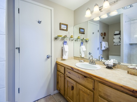 Step into your private bathroom featuring a spacious vanity with rustic wood cabinetry, fresh linens, and plenty of counter space for all your essentials.