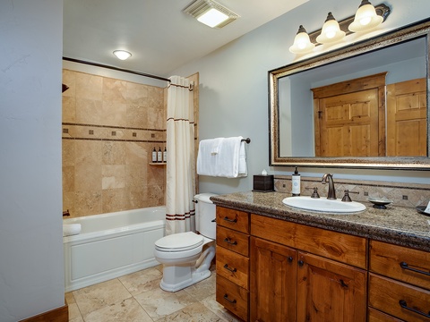 Unwind in your beautifully appointed bathroom, featuring warm wood cabinetry, granite counters, and a relaxing tub-shower combo—perfect for refreshing after a day of adventure.