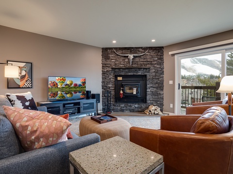 Unwind by the stone fireplace as you take in stunning mountain views through the balcony doors. Cozy seating and warm textures make this your perfect retreat after a day exploring.