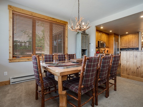 Gather around your spacious dining table under a striking antler chandelier, where rustic mountain charm meets comfort. The open kitchen awaits your culinary adventures, all bathed in natural light.