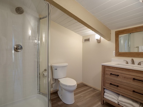 Your beautifully appointed bathroom features a gleaming walk-in shower, modern vanity with marble countertop, and warm wood accents that create a relaxing, spa-like retreat.