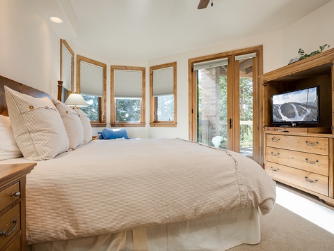 Sink into crisp linens on your plush bed, while natural light streams through wood-framed windows and glass doors opening to your private outdoor space—your restful mountain retreat awaits.