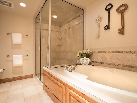 Unwind in your spa-inspired bathroom featuring a soaking tub and spacious walk-in shower. Fresh towels await, and charming vintage key decor adds character to your private retreat.