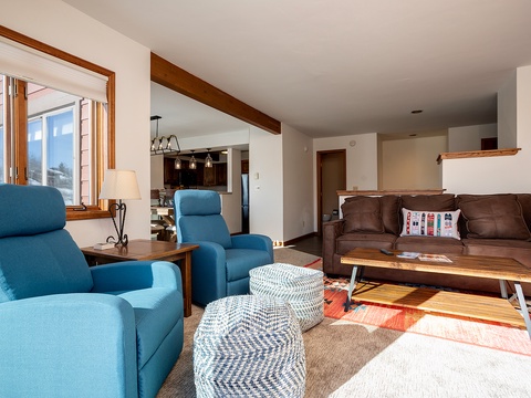 Sink into plush recliners and unwind in your bright, open-concept living space where warm wood beams and mountain light create the perfect retreat after a day of adventure.