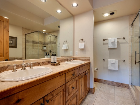 Step into your private spa retreat—a beautifully appointed bathroom with double vanities, elegant marble countertops, and a spacious walk-in shower inviting you to unwind after your mountain adventures.
