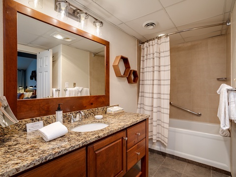 Relax in your spacious bathroom with granite countertops, warm wood cabinetry, and a full tub-shower combo. Fresh towels and thoughtful touches make it feel like home.