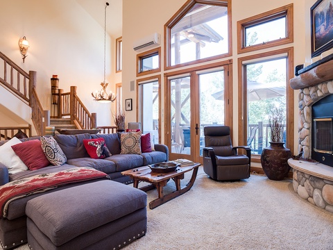 Step into your spacious alpine retreat where vaulted ceilings and floor-to-ceiling windows frame stunning mountain views. Sink into plush seating by the stone fireplace after a day of adventure.