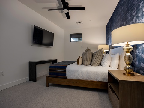 Your modern retreat awaits with crisp linens, warm ambient lighting, and a soothing blue accent wall. Cool off under the ceiling fan or relax with entertainment at your fingertips in this thoughtfully designed space.
