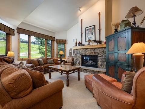 Curl up on plush sofas by the stone fireplace as natural light pours through tall windows, revealing views of rolling greens. Warm lamps and rustic touches create your perfect retreat.