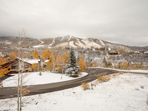 A scenic mountain resort area featuring ski slopes and surrounding residential buildings, showcasing the property's prime location near winter recreation in a snow-dusted alpine setting.