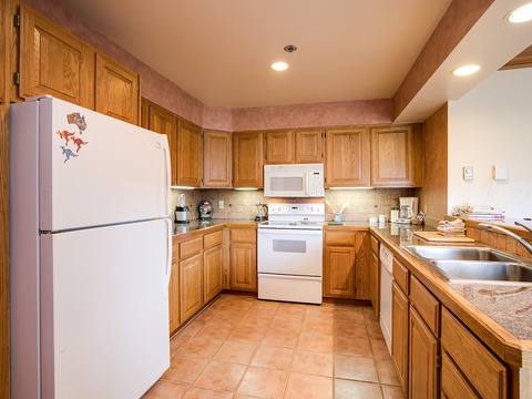 A fully equipped kitchen with oak cabinetry, modern appliances, and granite counters where you can prepare your favorite meals in comfort.