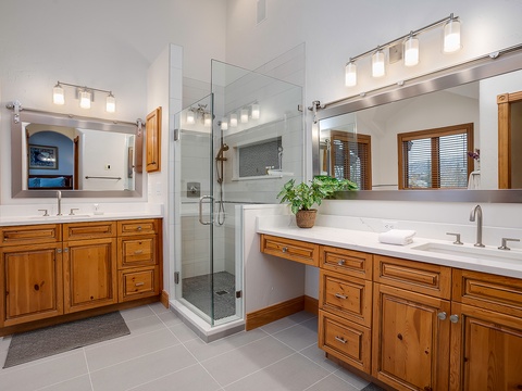 Unwind in your spacious en-suite with dual vanities, a glass-enclosed walk-in shower, and warm wood cabinetry that adds rustic charm to your morning routine.