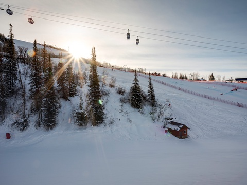 Ski resort nestled in snow-covered mountains with lifts and groomed slopes under a bright winter sun.