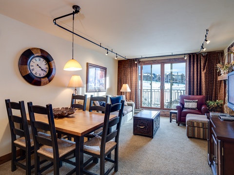 Your bright, open living space features cozy seating, a welcoming dining table, and balcony access with beautiful marina views—perfect for relaxing after mountain adventures.