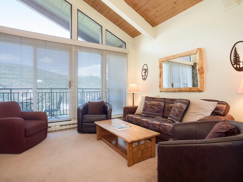 Settle into your cozy living room where soaring wood ceilings and mountain-lodge touches create the perfect après-ski sanctuary. Natural light floods through tall windows, inviting you to unwind on plush leather seating.