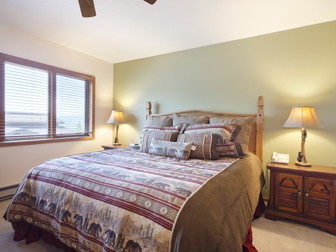 Sink into plush bedding and rustic charm in your peaceful bedroom retreat. Natural light streams through large windows while warm lamps create a cozy ambiance for your perfect mountain getaway.