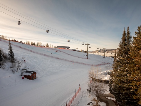 Ski resort area featuring snow-covered slopes, chair lifts, and alpine landscape during winter season at dusk.