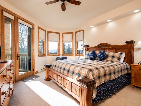 Your spacious master suite features a cozy king bed with handsome woodwork, a private balcony, and stunning mountain vistas framed by charming windows—perfect for restful mornings and peaceful evenings.