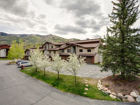 A mountain community property framed by spring blooms and evergreens, with convenient parking and scenic mountain views.