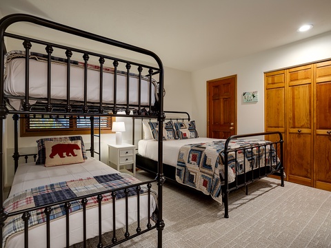 Cozy sleeping quarters with charming black metal bunk beds and rustic bedding, plus ample closet space to keep your belongings organized during your mountain getaway.