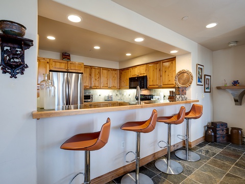 Your fully equipped kitchen features warm wood cabinetry, stainless steel appliances, and a welcoming breakfast bar with four seats—perfect for casual meals and morning coffee together.