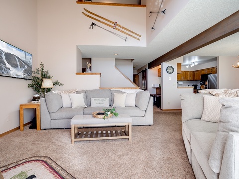 Sink into plush sofas and unwind in your spacious, light-filled living area with vaulted ceilings, rustic ski decor, and open sightlines to the kitchen—perfect for gathering after a day on the slopes.