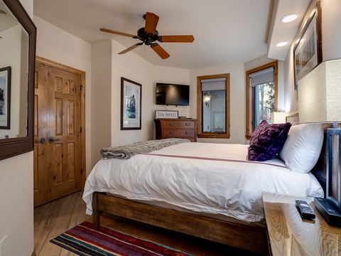 Sink into crisp white linens beneath the gentle spin of the ceiling fan as natural light fills your cozy retreat, complete with a flat-screen TV for unwinding after adventures.