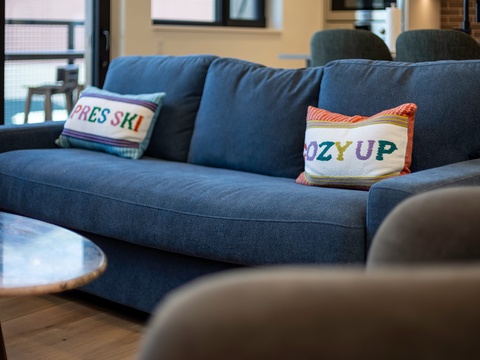 Sink into this plush sofa and unwind—colorful cushions and natural light make your downtime feel extra cozy.