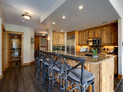 Gather around the breakfast bar in your fully-equipped kitchen, where warm wood cabinetry and modern appliances set the stage for memorable meals together.