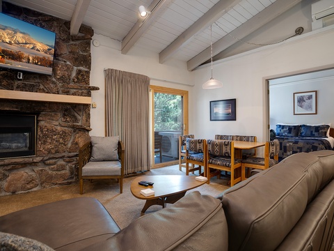 Unwind in your cozy mountain retreat with a crackling stone fireplace, plush seating, and vaulted ceilings that create an inviting, open atmosphere perfect for relaxation.
