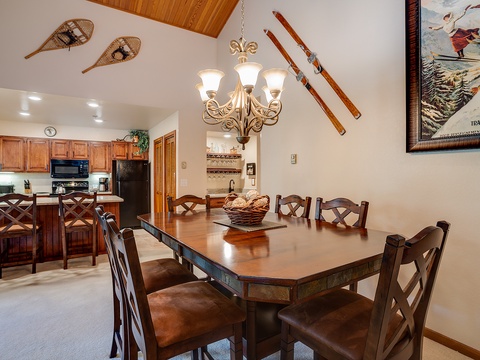 Step into your alpine haven where rustic charm meets modern comfort—vintage skis and snowshoes adorn vaulted ceilings, inviting you to gather around a handsome dining table for meals after mountain adventures.