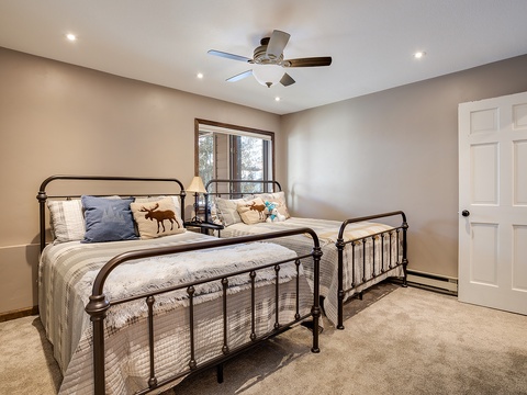 Rest easy in this cozy bedroom with two inviting beds, soft carpeting, and a ceiling fan to keep you comfortable. Natural light streams through the window, creating a peaceful retreat after your adventures.